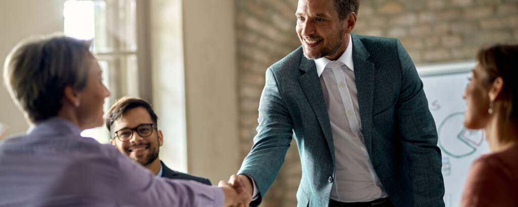 Empresario dándole la mano a un cliente en una reunión, ejemplificando el enfoque customer centric en la innovación empresarial.